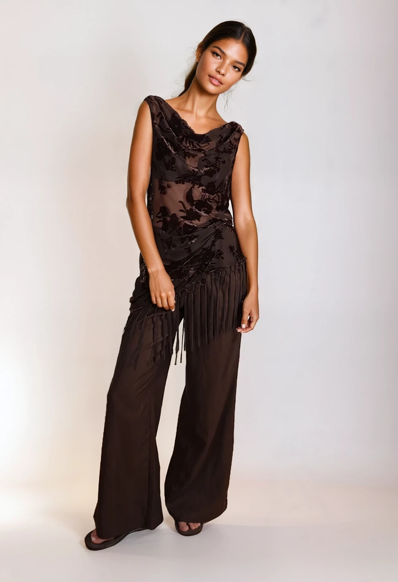 Woman wearing a brown fringe dress against a white background